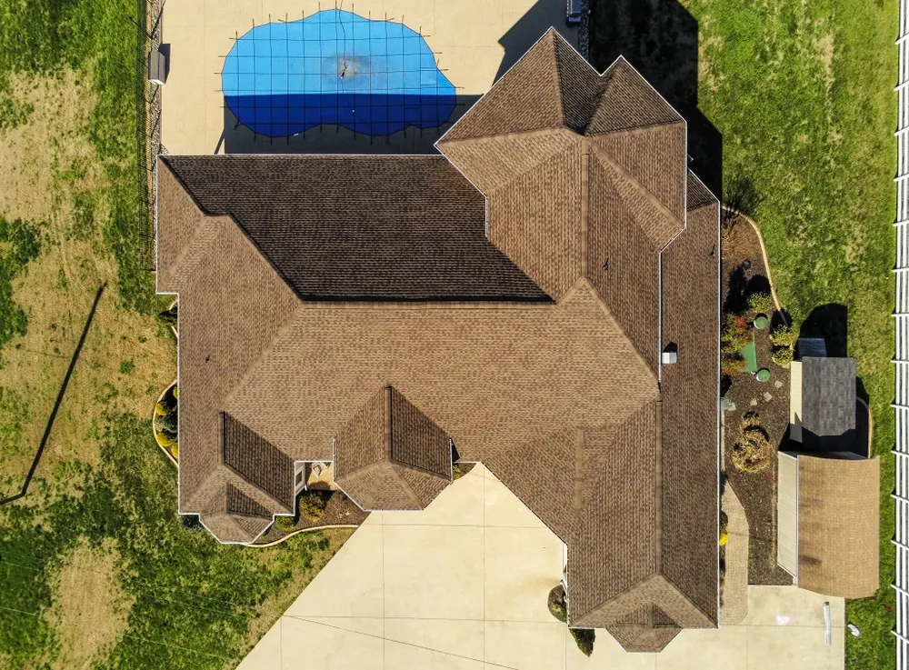 Aerial view of a large brown architectural shingle roof on a luxury Dunkirk, MD home with a covered swimming pool (Summit Exteriors roof replacement in Dunkirk, MD)