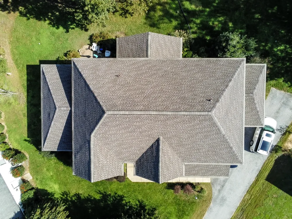 Aerial drone view of a complex multi-gable home in Lusby, MD with a freshly installed grey architectural shingle roof