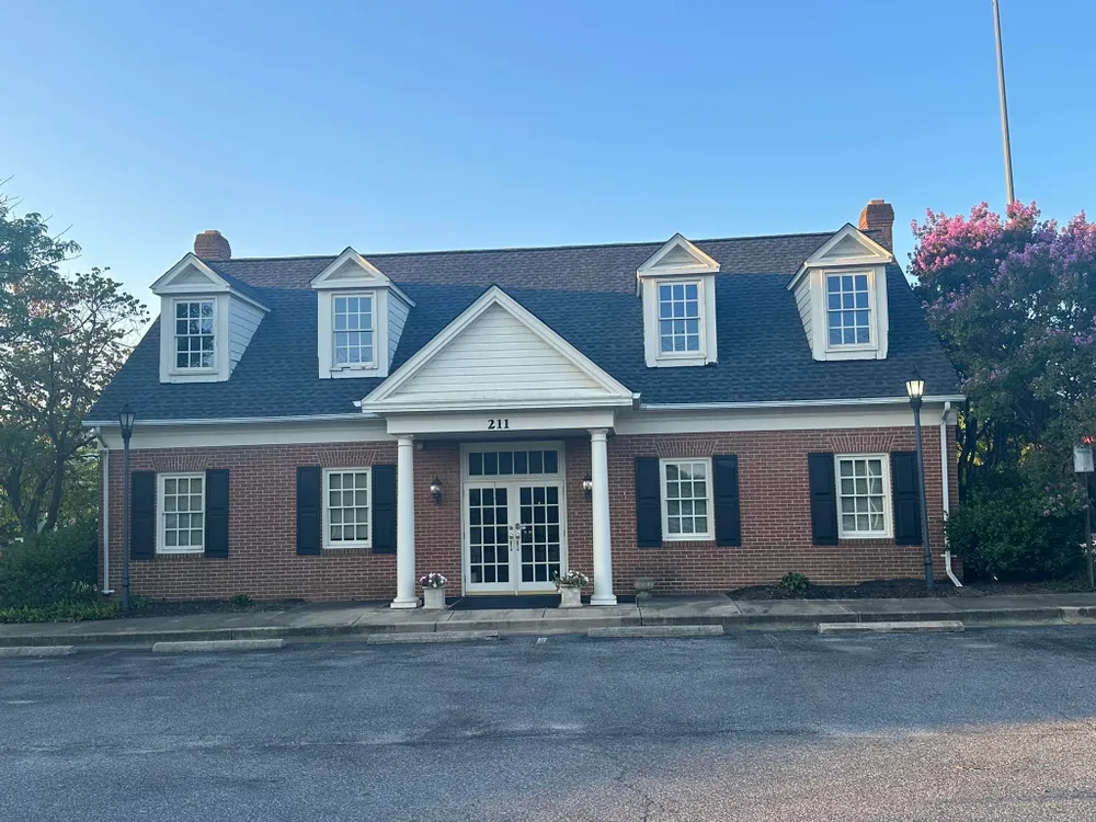Brick Cape Cod commercial building in Leonardtown, MD with new black architectural shingles and four white dormers