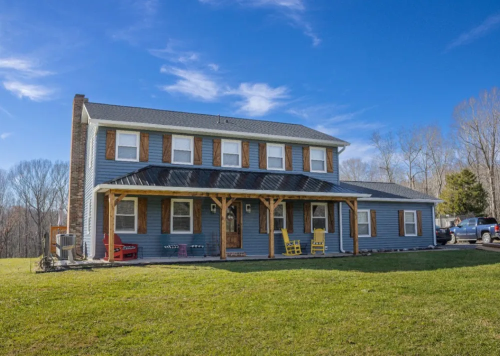Two-story Mechanicsville, MD farmhouse with new blue vinyl siding, board-and-batten accents, cedar shutters and a metal porch roof