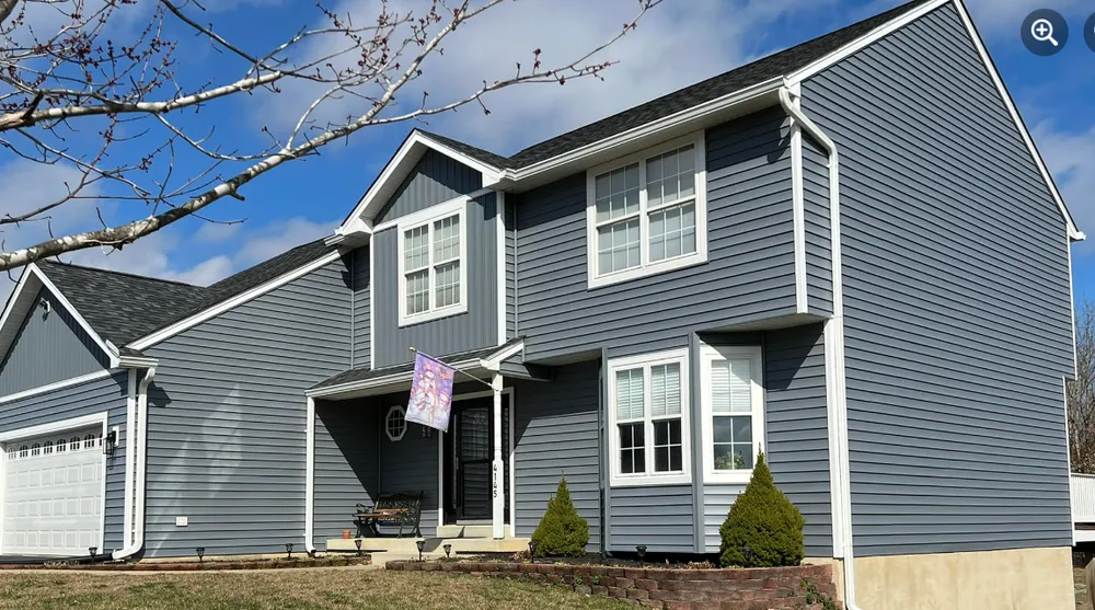 Two-story Lexington Park, MD home with new blue vinyl siding, white trim, and white aluminum gutters by Summit Exteriors