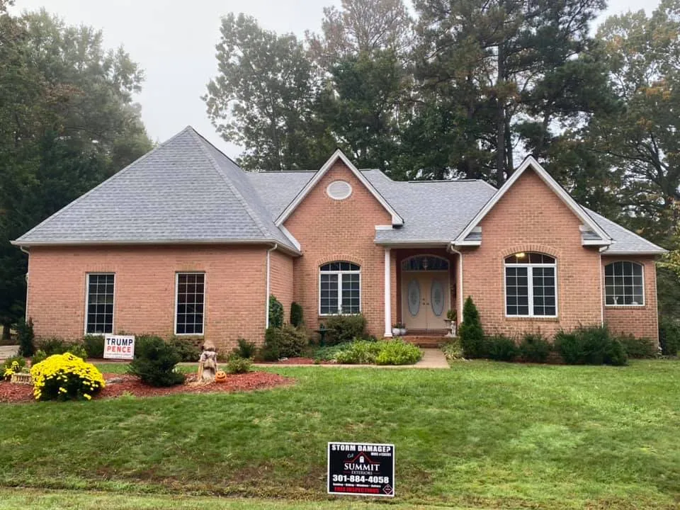Brick rancher with arched windows in La Plata, MD featuring a new grey architectural shingle roof and Summit Exteriors Storm Damage yard sign