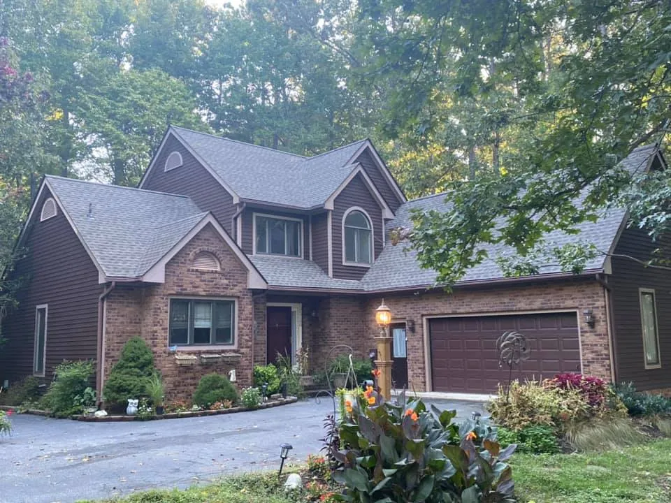 Brick Tudor-style two-story home in Dunkirk, MD nestled in the woods with a new brown architectural shingle roof installed by Summit Exteriors
