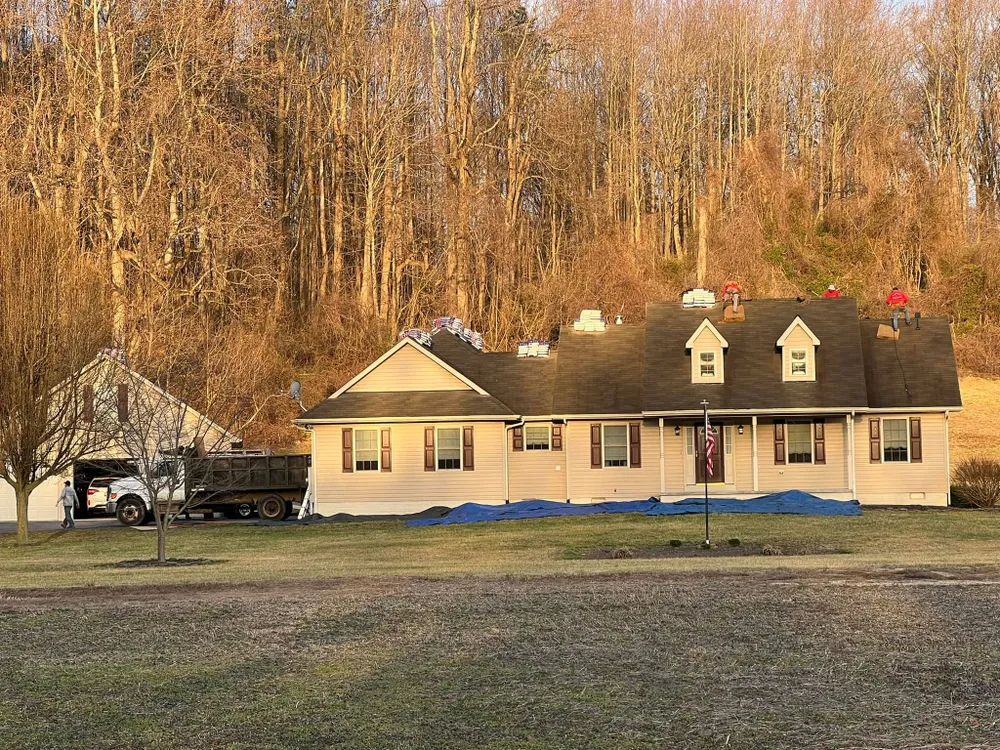 Cape Cod home in Mechanicsville, MD with shingle bundles and dump trailer on site during a Summit Exteriors roof replacement