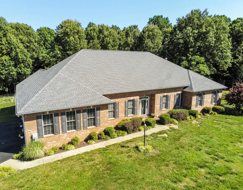 Aerial drone shot of a brick rancher in Clinton, MD with a new gray hip architectural shingle roof installed by Summit Exteriors
