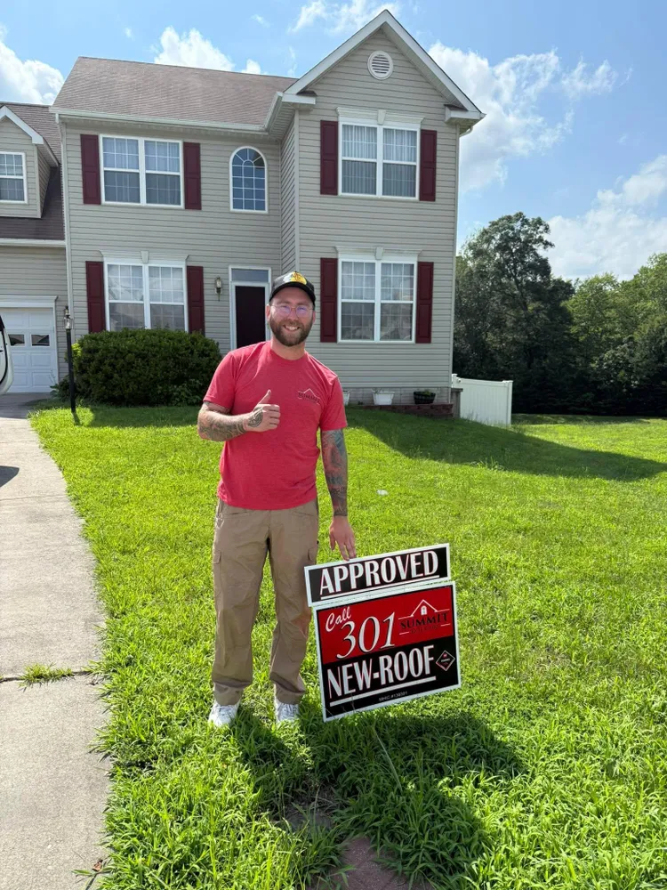 Summit Exteriors team member giving a thumbs up next to an Approved insurance claim yard sign in front of a two-story Waldorf, MD home