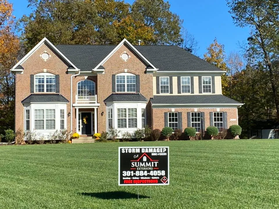 Large two-story brick colonial in Bowie, MD with a new black architectural shingle roof and Summit Exteriors Storm Damage yard sign on the lawn