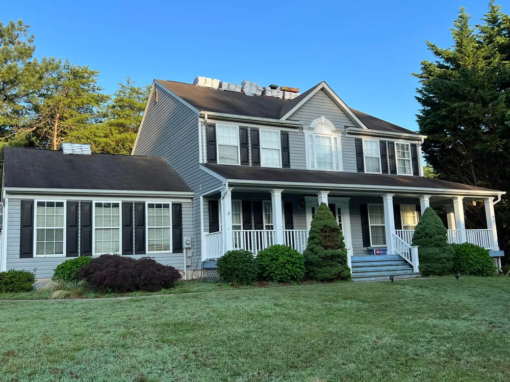 Two-story Prince Frederick, MD colonial with shingle bundles staged on the roof during a Summit Exteriors roof replacement