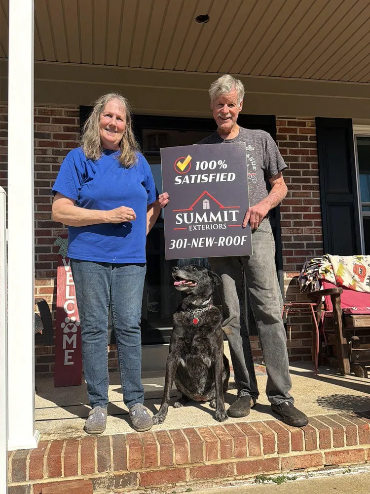 Happy Summit Exteriors customers in Mechanicsville, MD holding a 100% Satisfied yard sign with their dog after a roof replacement