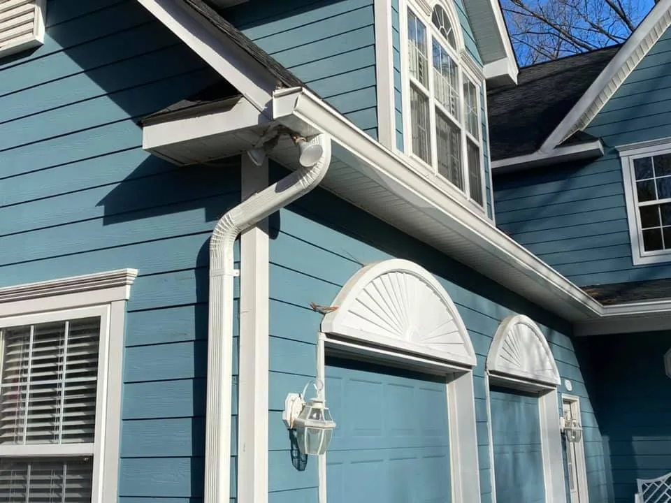 Close-up of new white seamless aluminum gutters and downspout on a blue Hardie-sided home in Chesapeake Beach, MD