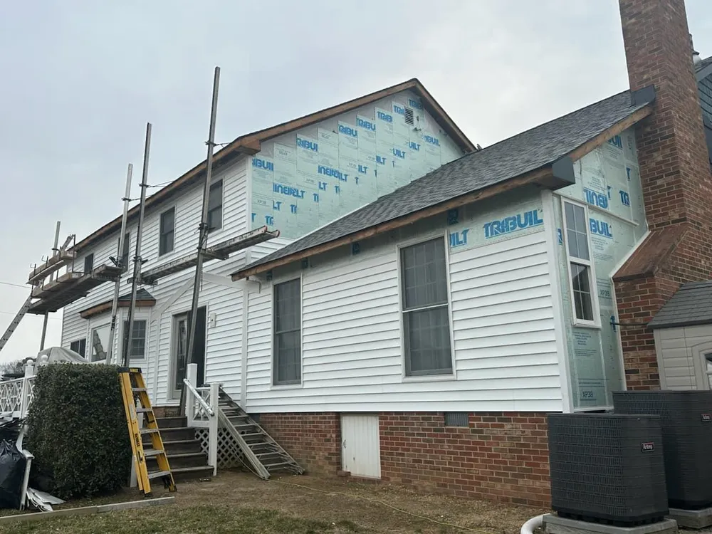 Two-story Leonardtown, MD home wrapped in TriBuilt house wrap with new white vinyl siding being installed by Summit Exteriors