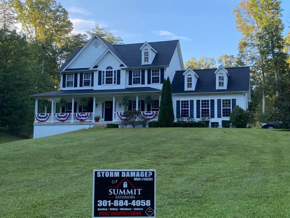Two-story white colonial in Mechanicsville, MD with patriotic bunting and Summit Exteriors Storm Damage yard sign in the front yard