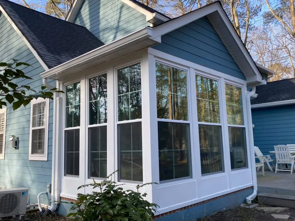 New blue Hardie-style sided sunroom addition with floor-to-ceiling white windows on a Chesapeake Beach, MD home by Summit Exteriors, completed as part of a siding installation job in Chesapeake Beach, MD