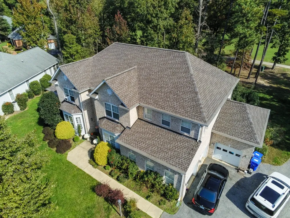 Two-story brick home in Owings, MD with a new brown architectural shingle roof and seamless gutters