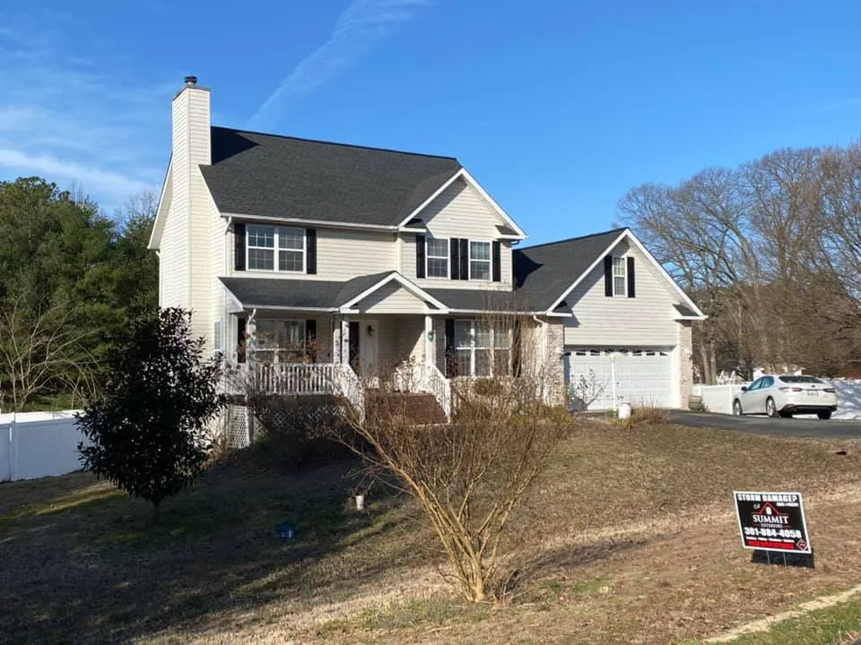 Two-story tan vinyl-sided colonial in Lusby, MD with a brand new charcoal architectural shingle roof and Summit Exteriors yard sign