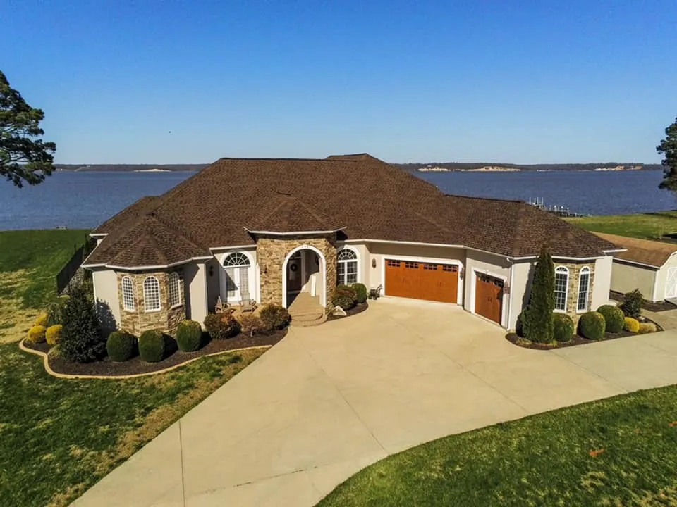 Aerial view of a waterfront luxury rancher in Solomons, MD with stone accents and a freshly installed brown architectural shingle roof