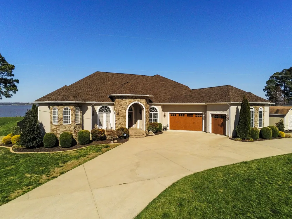 Waterfront stone and stucco rancher in Solomons, MD with a new brown architectural shingle roof overlooking the Patuxent River